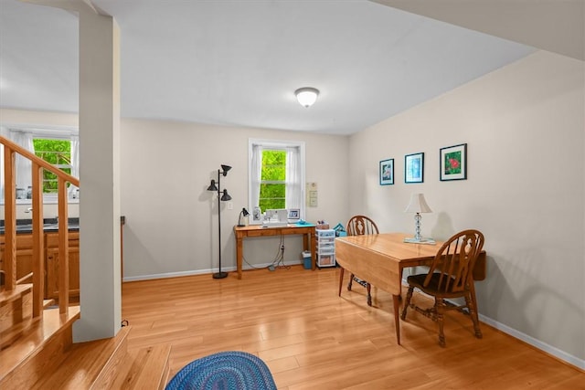 dining space featuring stairs, light wood-type flooring, and baseboards