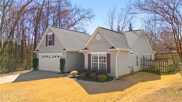 view of home's exterior with roof with shingles, driveway, and fence