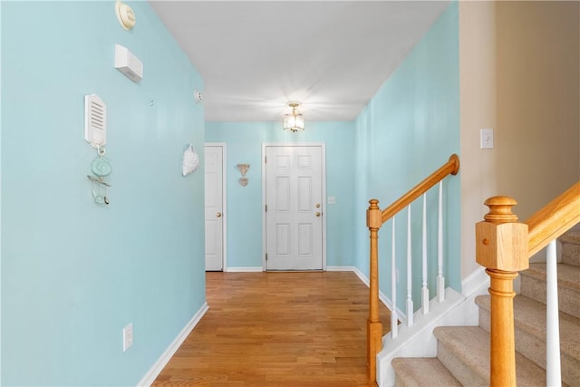 foyer with stairway, baseboards, and wood finished floors