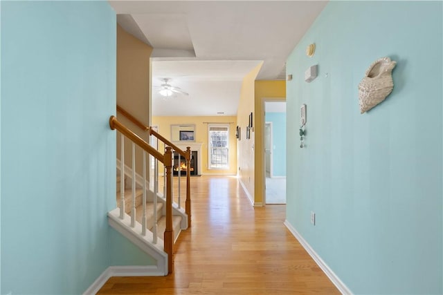 hall featuring light wood finished floors, stairs, and baseboards