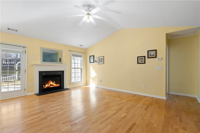 unfurnished living room with visible vents, lofted ceiling, a fireplace with flush hearth, ceiling fan, and light wood-style floors