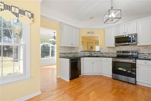 kitchen with stainless steel appliances, dark countertops, tasteful backsplash, an inviting chandelier, and white cabinets