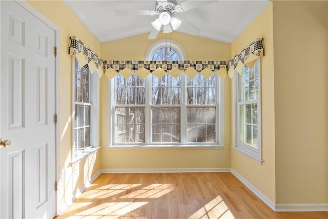 unfurnished dining area featuring ceiling fan, vaulted ceiling, baseboards, and wood finished floors