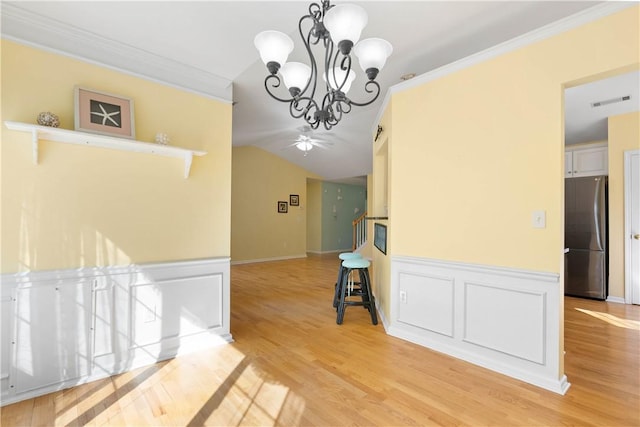 hall with a notable chandelier, crown molding, visible vents, vaulted ceiling, and light wood-type flooring