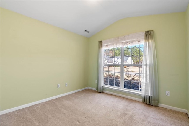 carpeted empty room with vaulted ceiling, visible vents, and baseboards