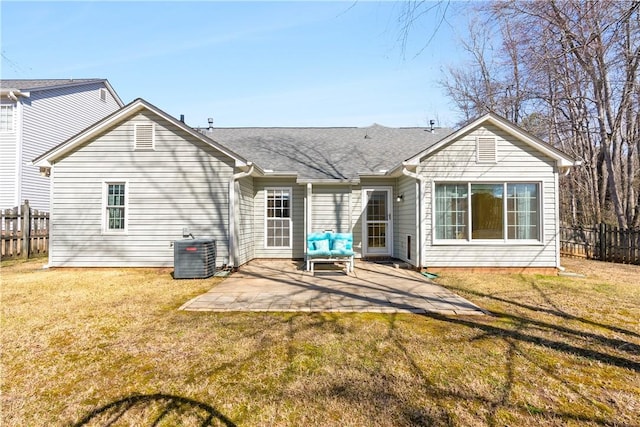 back of house with central air condition unit, fence, roof with shingles, a lawn, and a patio area