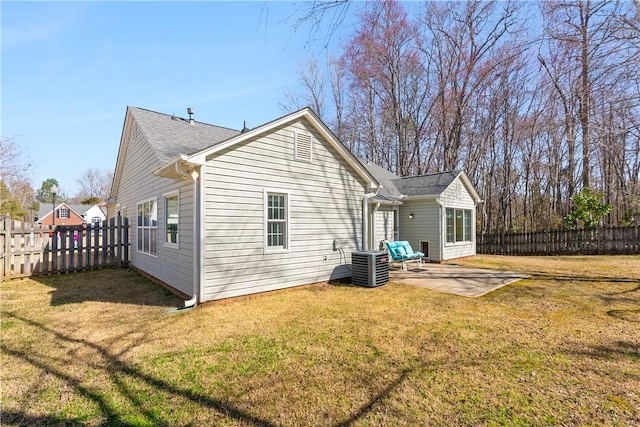 rear view of property featuring a patio area, central AC, a yard, and a fenced backyard