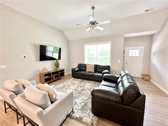 living room with lofted ceiling, ceiling fan, light wood-type flooring, and baseboards