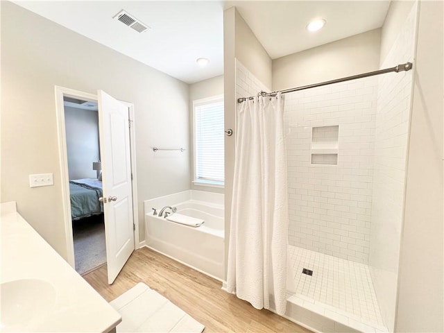 ensuite bathroom featuring ensuite bathroom, a garden tub, wood finished floors, visible vents, and a shower stall