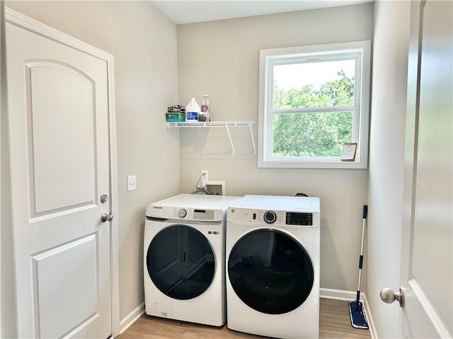 clothes washing area featuring light wood finished floors, laundry area, separate washer and dryer, and baseboards