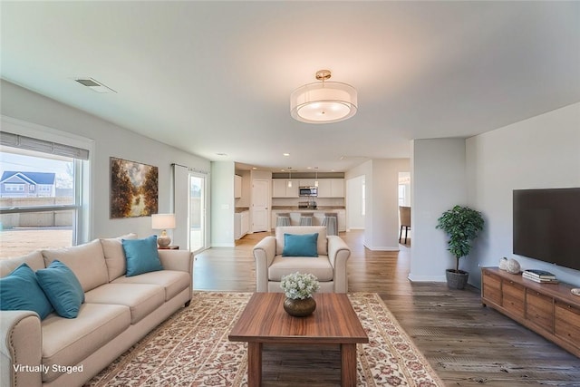 living area featuring light wood-type flooring, baseboards, and visible vents