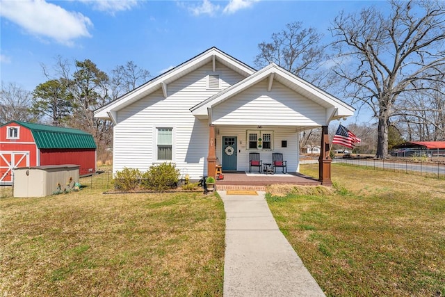 bungalow featuring a front yard, fence, a porch, and an outdoor structure