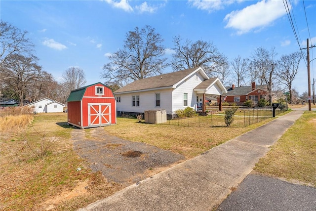 view of front facade with an outbuilding, a gambrel roof, a storage shed, fence, and a front lawn