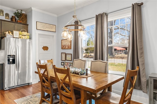 dining area with a wealth of natural light, crown molding, wood finished floors, and an inviting chandelier