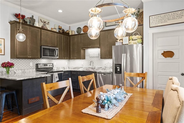 kitchen with ornamental molding, dark brown cabinets, appliances with stainless steel finishes, and decorative backsplash