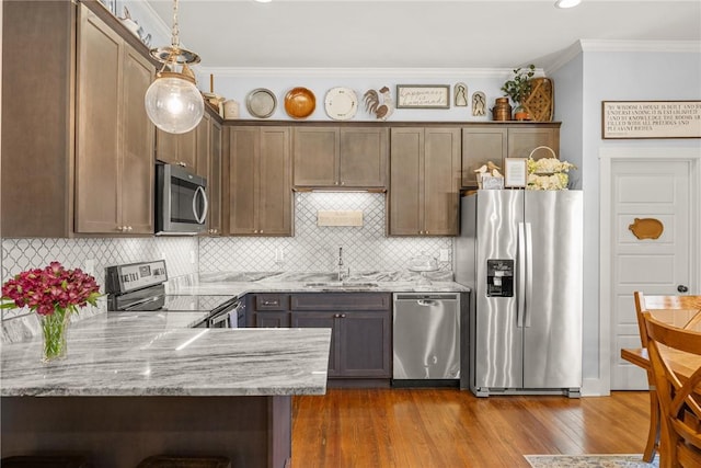 kitchen with stainless steel appliances, a sink, ornamental molding, decorative backsplash, and dark wood finished floors