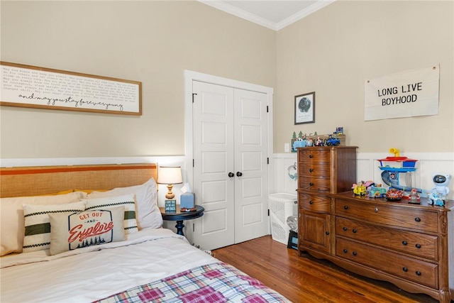 bedroom featuring a closet, a wainscoted wall, crown molding, and wood finished floors