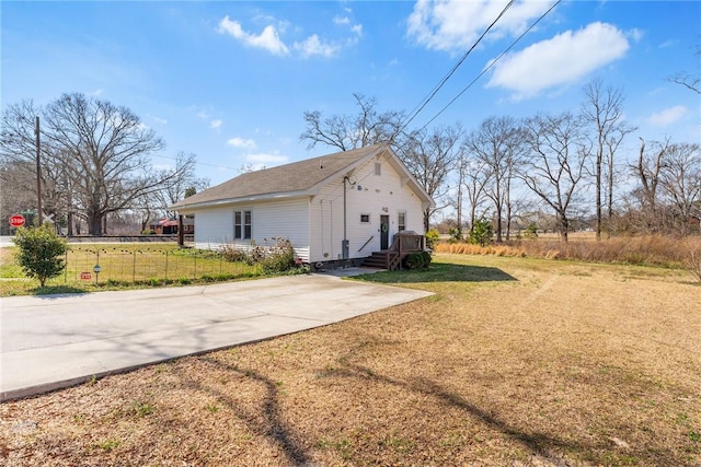 view of side of home featuring driveway, fence, and a yard