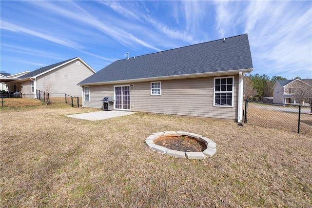 rear view of house with roof with shingles, a yard, a patio, and fence