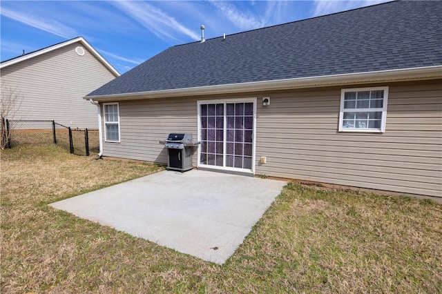 rear view of property featuring a patio area, a shingled roof, fence, and a yard