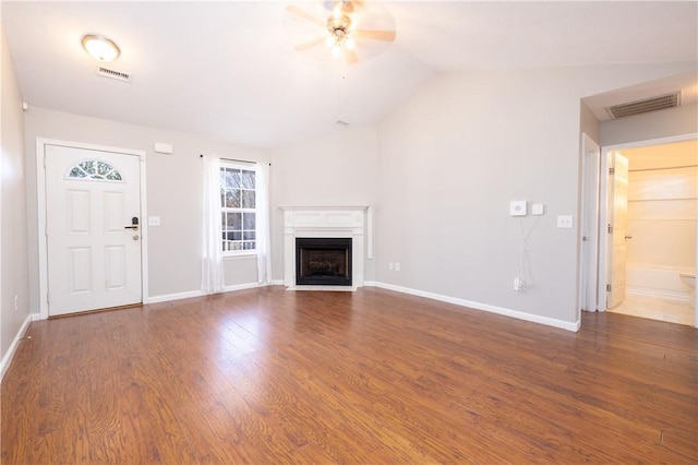 unfurnished living room with baseboards, visible vents, a fireplace with flush hearth, wood finished floors, and vaulted ceiling