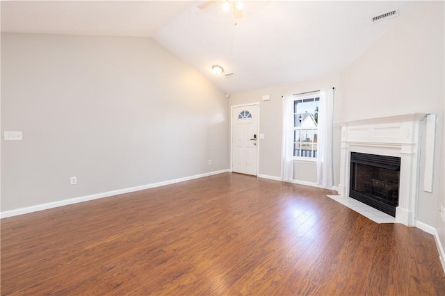 unfurnished living room with ceiling fan, a fireplace with flush hearth, wood finished floors, baseboards, and vaulted ceiling