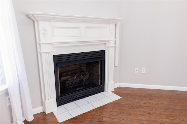 interior details featuring wood finished floors, a fireplace with flush hearth, and baseboards