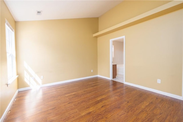 spare room featuring plenty of natural light, dark wood finished floors, and baseboards