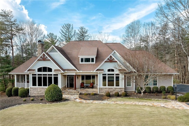 view of front of home with a front yard, stone siding, and a chimney