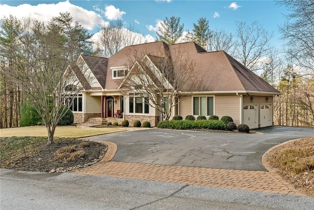 craftsman-style house featuring aphalt driveway, stone siding, and a garage