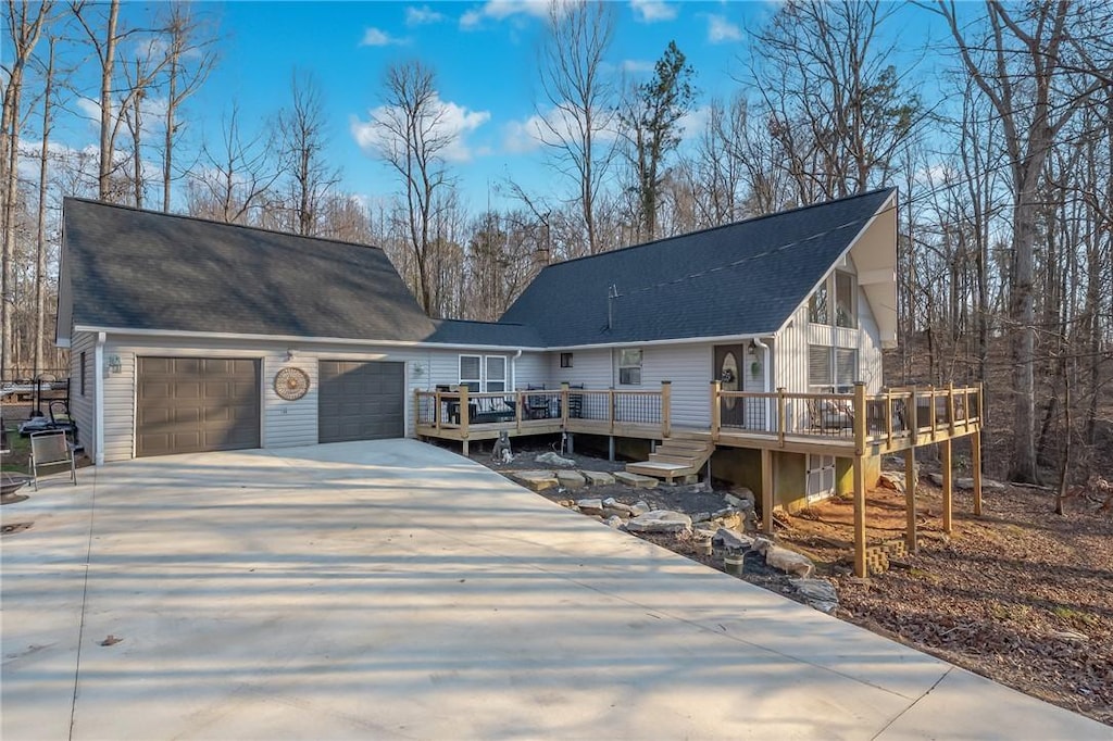 view of front of home featuring driveway, an attached garage, roof with shingles, and a wooden deck