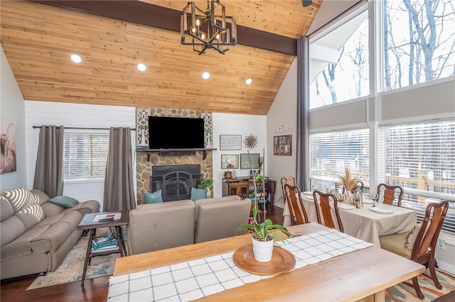 dining area featuring wooden ceiling, a healthy amount of sunlight, a stone fireplace, and wood finished floors