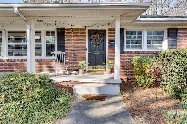 property entrance with a porch and brick siding