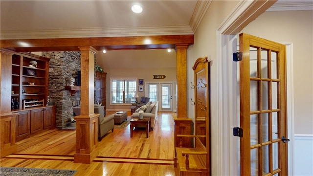 hallway with decorative columns, ornamental molding, light wood-style flooring, and french doors