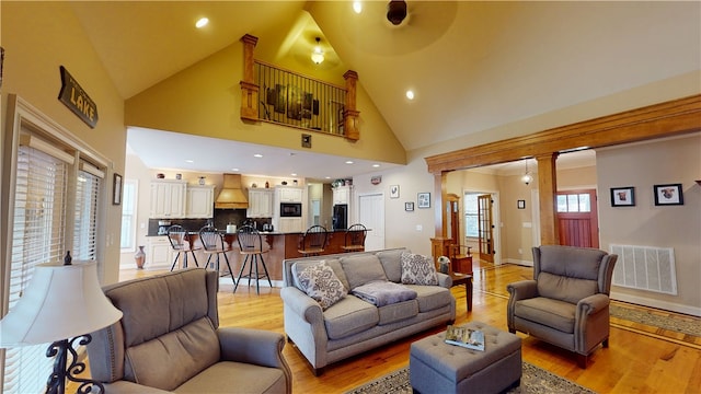 living room with light wood-style floors, visible vents, and high vaulted ceiling