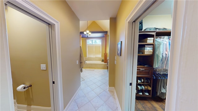 hallway featuring baseboards, a chandelier, and tile patterned floors