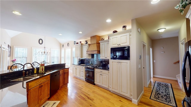 kitchen featuring tasteful backsplash, vaulted ceiling, a sink, premium range hood, and black appliances