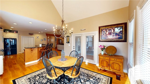 dining area with baseboards, an inviting chandelier, light wood-type flooring, high vaulted ceiling, and recessed lighting