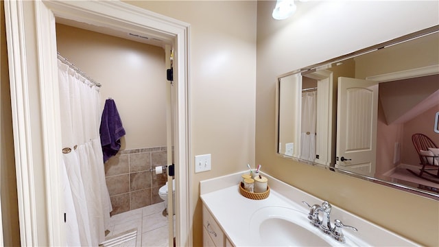 bathroom featuring toilet, tile patterned floors, tile walls, and vanity