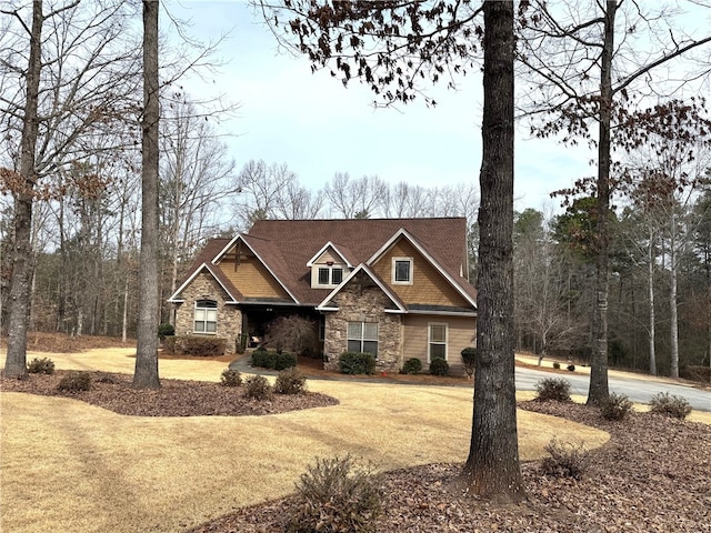 craftsman-style house with stone siding and a front lawn