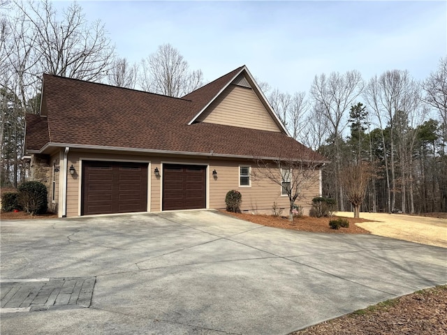 view of front of property with a garage, driveway, and roof with shingles