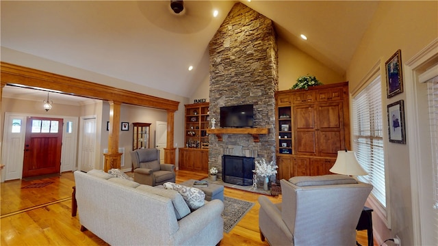 living area with light wood-style floors, recessed lighting, a fireplace, and high vaulted ceiling