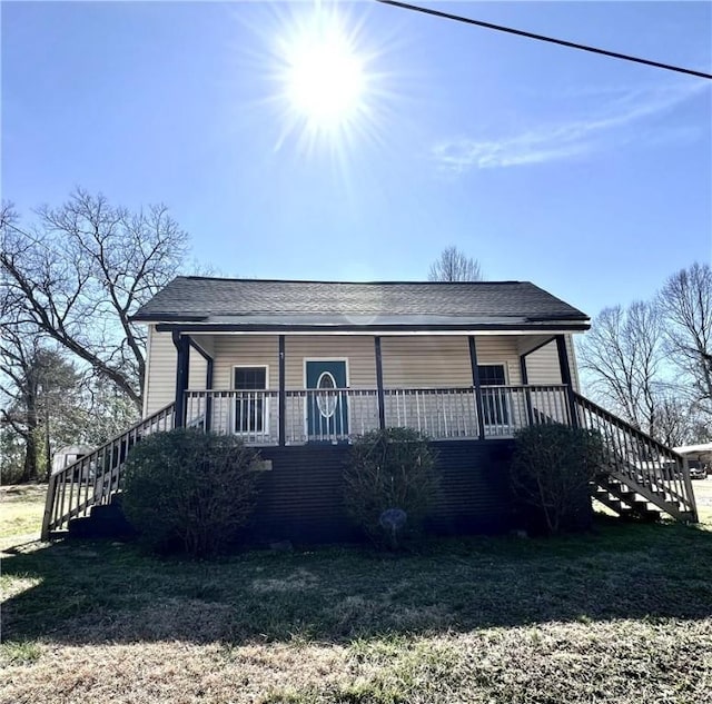 view of front of home featuring covered porch, stairs, and a front yard