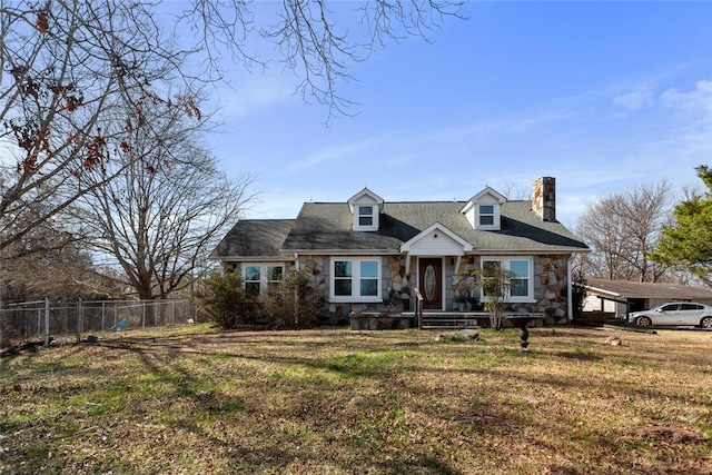 cape cod house featuring an attached carport, fence, stone siding, a front lawn, and a chimney