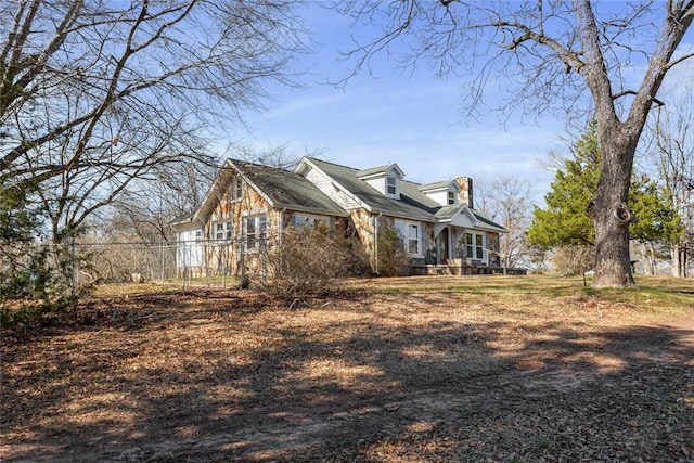 view of home's exterior with stone siding and fence