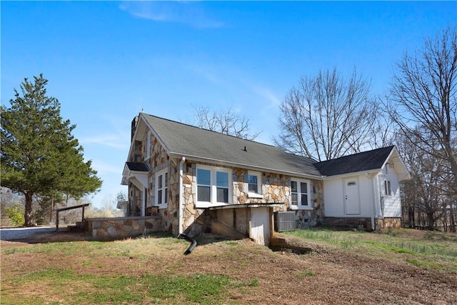 back of house featuring stone siding and central AC