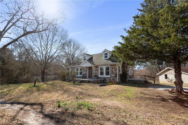 cape cod house with stone siding and fence