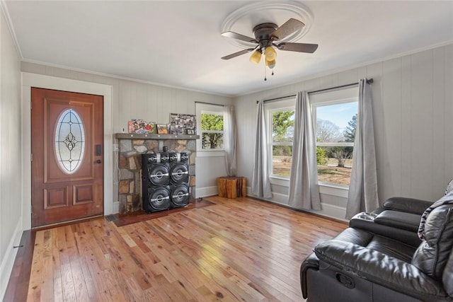 interior space featuring light wood finished floors, a ceiling fan, and crown molding