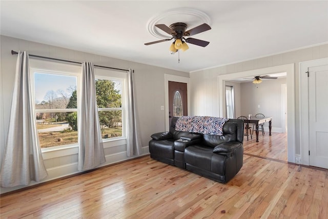 living area with light wood finished floors, ceiling fan, and baseboards