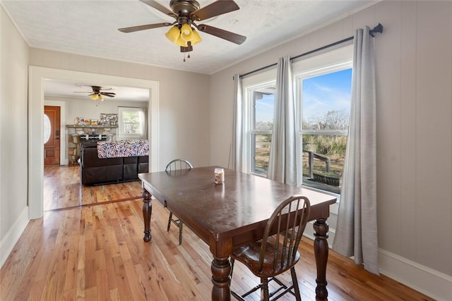 dining room featuring light wood-style floors, ornamental molding, baseboards, and a ceiling fan